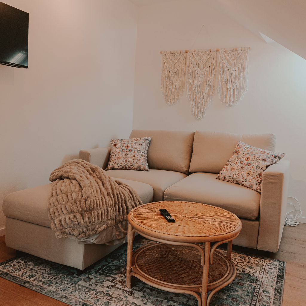 Gemütliche Sofaecke im Boho-Stil mit Rattan-Couchtisch und gemustertem Teppich
