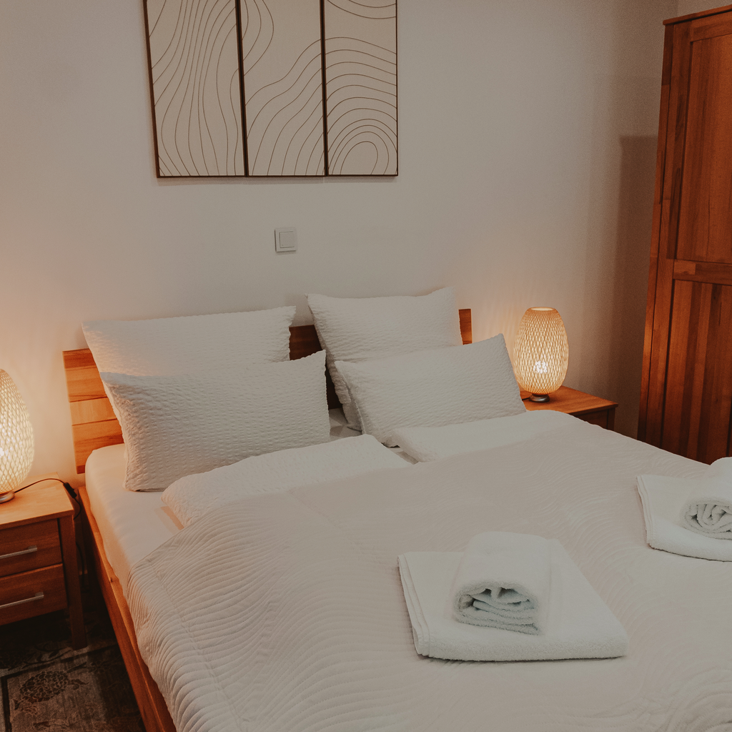 Schlafzimmer mit Holzmöbeln, Doppelbett und warmer Abendbeleuchtung